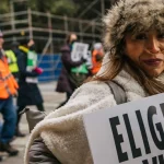 A pro-life demonstrator marches during the "Right To Life" rally on Jan. 15, 2022, in Dallas, Texas. Her sign says "ELIGE LA VIDA," which translates to "CHOOSE LIFE" in English. Abortion continues to be a pervasive political issue — even in the workplace.