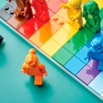 Monochrome Lego people, including a person of color, run on an LGBTQ+ pride flag. Lego is changing its public-facing approach to DEI.
