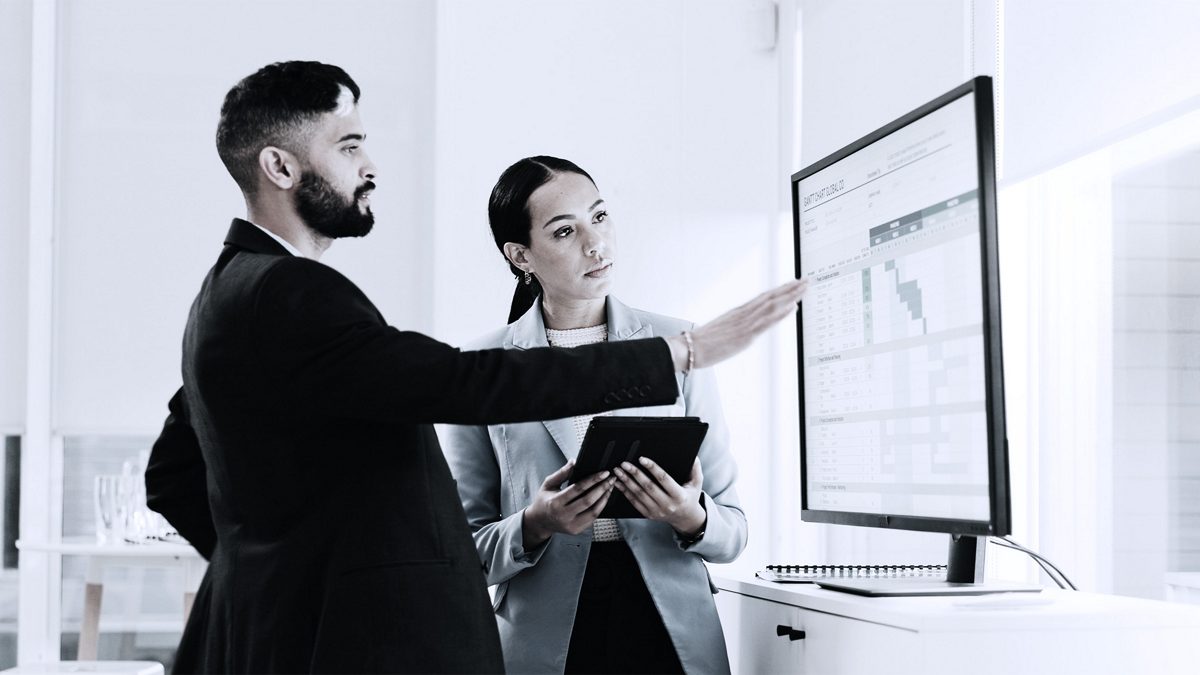 Two business people looking at a screen with data analytics.
